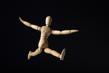 Wooden mannequin happy jump on black background. Minimal happiness concept.