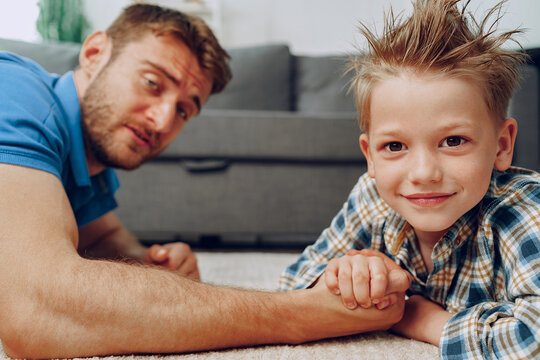 Father and son arm wrestling on carpet at home