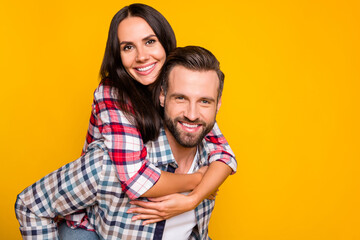 Photo portrait of woman riding on man's back isolated on vivid yellow colored background with blank space