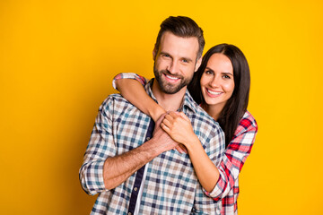 Portrait of lovely cute tender cheerful affectionate couple embracing isolated over bright yellow color background