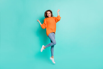 Fototapeta na wymiar Full size photo of young happy positive excited girl jumping in victory wear orange pullover isolated on teal color background