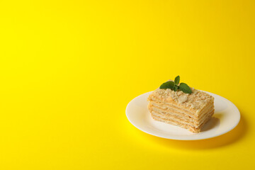 Plate with delicious Napoleon cake on yellow background