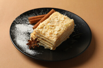 Plate with piece of Napoleon cake with cinnamon on craft background