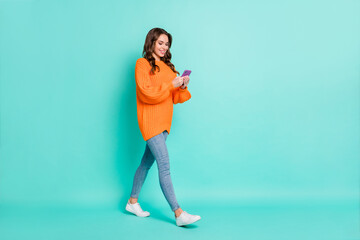 Full size profile side photo of young beautiful positive smiling girl go walk using smartphone...