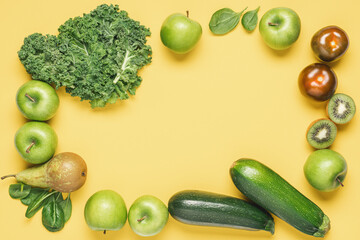 Green vegetables and fruits on yellow background. Apples, pears, kale salad, spinach, kiwi, green tomatoes, zucchini