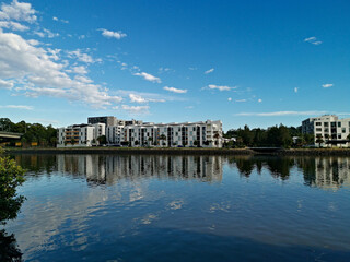 Fototapeta premium Beautiful view of a river with reflections of modern apartment buildings, blue sky and trees on water, Parramatta river, Wilson Park, Silverwater, Sydney, New South Wales, Australia 