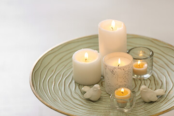 Fototapeta na wymiar Beautiful burning candles on tray against light background
