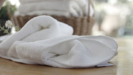 Towel placed on basket, white table top, bottle of liquid soap, spa set for bathing in the bathroom, copy space, bathroom window.