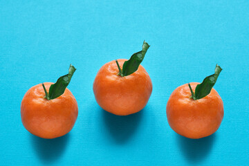 Ripe bright tangerines with green leaves on a turquoise background