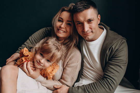 Photoshoot Of A Happy Young Family. Dad, Mom And Daughter. Studio Photography.