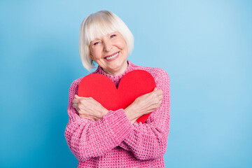 Photo portrait of old woman hugging big red heart card isolated on pastel blue colored background