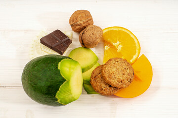 Composition of fruit on a white wooden table, Avogado, Nuts, Orange and chocolate chip cookies