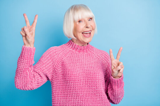 Photo portrait of excited cheerful old lady showing two v-signs isolated on pastel blue colored background
