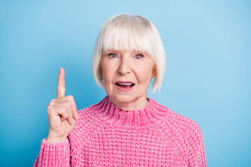 Photo portrait of confused old lady raising finger up isolated on pastel blue colored background