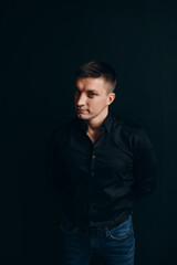 Naklejka premium Portrait of a successful businessman. The guy in the black shirt. Black background.
