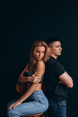 Photoshoot of a young couple in love. The solitude of a guy and a girl. Studio photography. Black background.