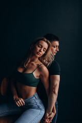 Photoshoot of a young couple in love. The solitude of a guy and a girl. Studio photography. Black background.