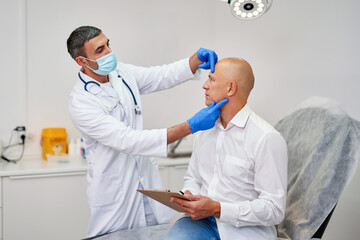 Doctor with man before aesthetic operation in medical clinic.