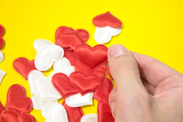 Many small hearts are held in his hands, they are red and white on a yellow background.