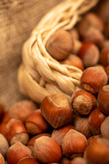 Hazelnuts in a wicker basket and loose nuts. It's time for the autumn harvest. Close-up, selective focus.