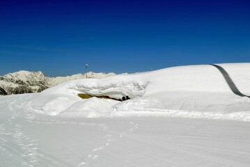 High snowdrifts against the background of fir trees and blue sky.