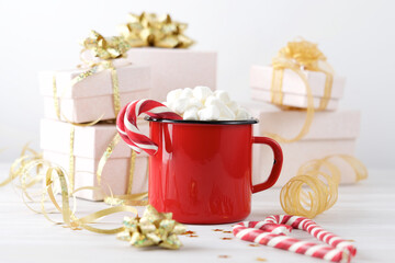 Hot drink with marshmallows and сandy cane in red cup on white background. Holiday festive celebration greeting card 