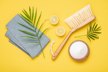 Eco brush, rag, lemon and soda on Illuminating yellow background. Flat lay eco cleaning products....