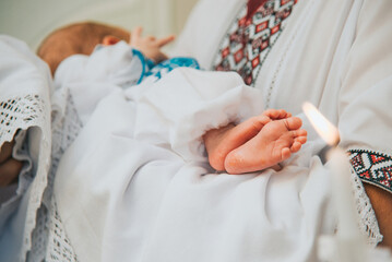 Godfather holds baby in church at sacrament of baptism.