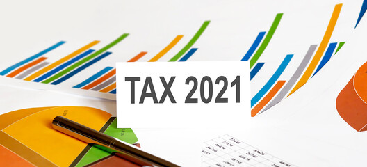 TAX 2021 text on paper on chart background with pen