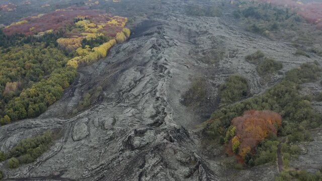 Scenic aerial shoot of autumn on Etna volcano in Sicily, Italy. Birches, secular oaks, holm oaks, turkey oaks, beeches and maples with typical autumn colors with lava flows.