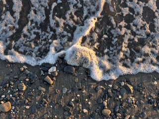 Pebbles in the beach and flowing sea water