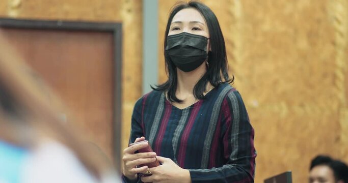 Asian Female Professor With Face Mask Explains To University Student In Classroom, COVID-19 Virus Protection, New Normal Lifestyle