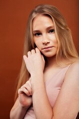 young pretty girl with blond hair posing cheerful on brown background, lifestyle people concept