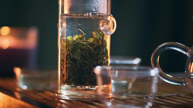 Tea ceremony. Close up shot of the glass tea pot with green loose tea soaking inside.