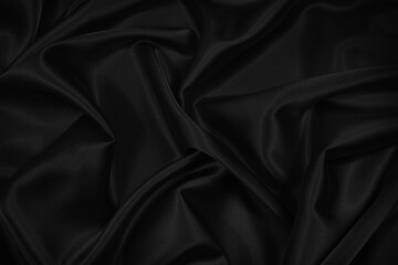 Abstract black background. Black silk satin fabric texture background. Beautiful soft folds on the...