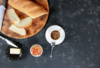 Breakfast. Fresh homemade bread and cup of coffee on a black background. Butter and sweet. Flat lay. Top view. Copy space