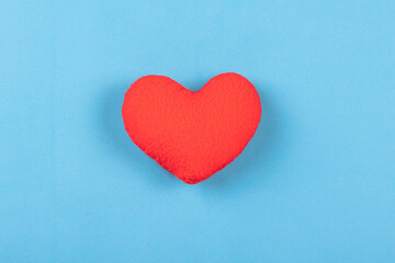 Obraz premium Red decorative pillow in shape of heart on blue background.