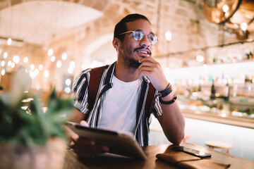 Pensive ethnic man with tablet in cafe
