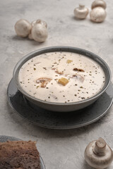 Vegetarian soup with coconut cream and mushrooms next to raw champignons and slices of bread