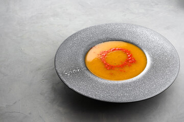 Pumpkin soup sprinkled with paprika in a gray plate with large margins