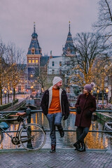 couple on city trip Amsterdam Netherlands canals with Christmas lights during December, canal...