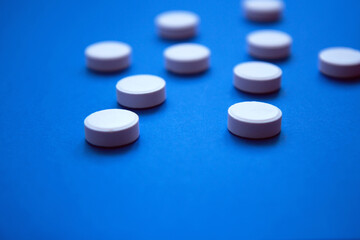 Obraz na płótnie Canvas Set of white pills on blue background. Pills background. White tablets on a blue background