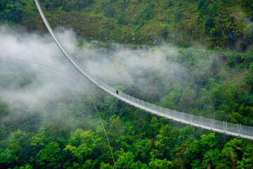 A solo walk in the midst of nature ,  a person crosses the suspension bridge connecting Baglung and Parbat districts of Nepal . Image taken in 2020 