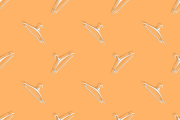 Clothes hanger on an orange background. Clothes hangers seamless pattern.