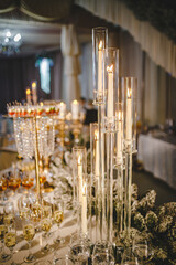 composition of candles in the form of a staircase. long luxury sumptuous decorated banquet table. high floating candles, crystal and gold ,champagne in glasses flute, appetizer and cold cuts