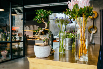 Different amazing flowers in vases on brass counter in flower shop loft modern interior. Floral design studio, decorations and compositions, gifts. Small business concept.