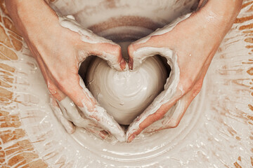 Woman working on the potter's wheel. Artisan making a cup from clay pot. Workshop of handmade...
