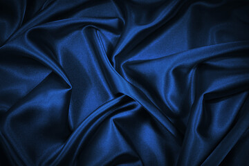 Abstract blue black background. Blue silk satin texture background. Beautiful soft wavy folds on...