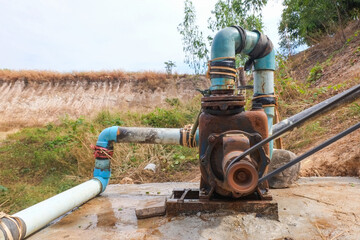 Old water pump connected to the PVC pipe running close up.