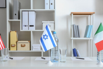 Flags of Israel, USA and Italy on table in embassy office